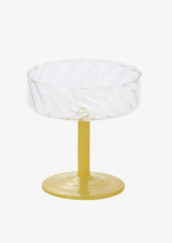 A fluted coupe glass with opaque yellow glass stem.