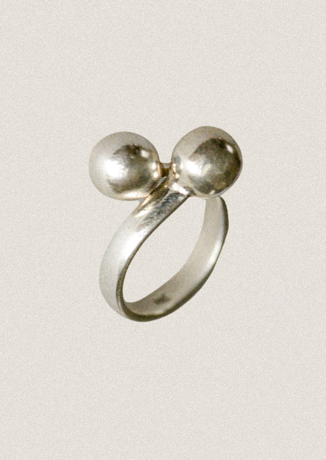 Silver ring with two spherical shapes on a light gray background