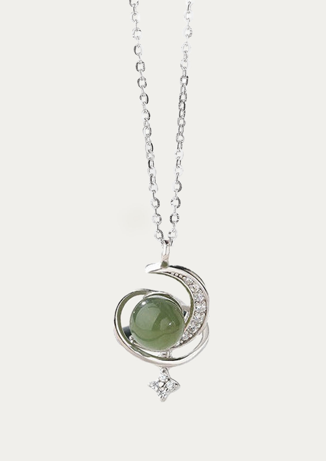 A sterling silver necklace with a moon and star charm holding a jade stone in the center.