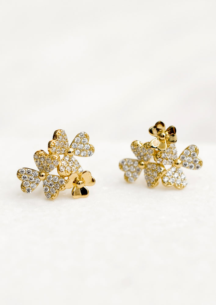 Gold stud earrings in shape of three flower cluster with clear crystals.