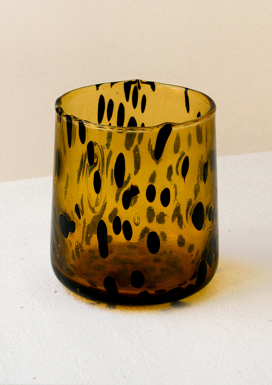 A dark yellow drinking glass with black abstract spots.