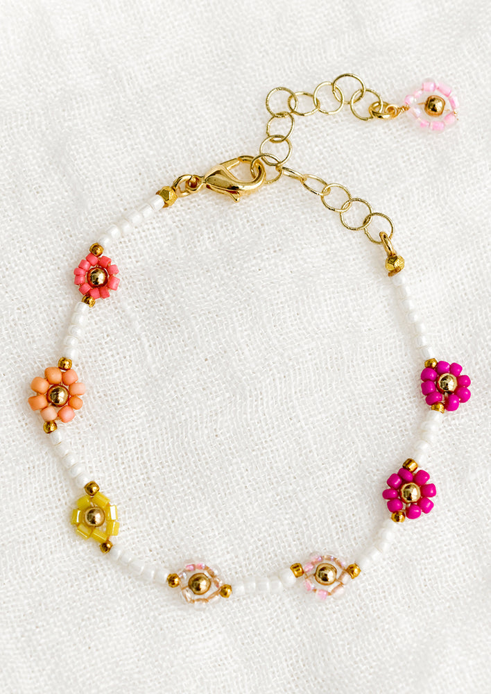 A white beaded bracelet with pink and yellow beaded flowers.