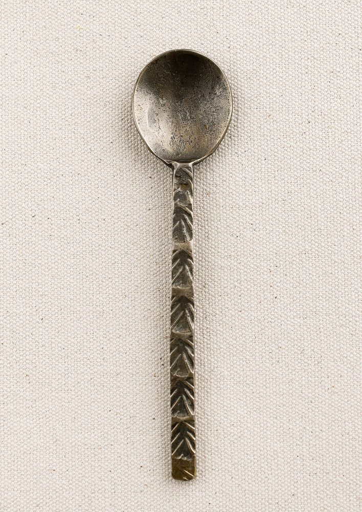 A brass spoon with textured handle.