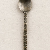 1: A brass spoon with textured handle.