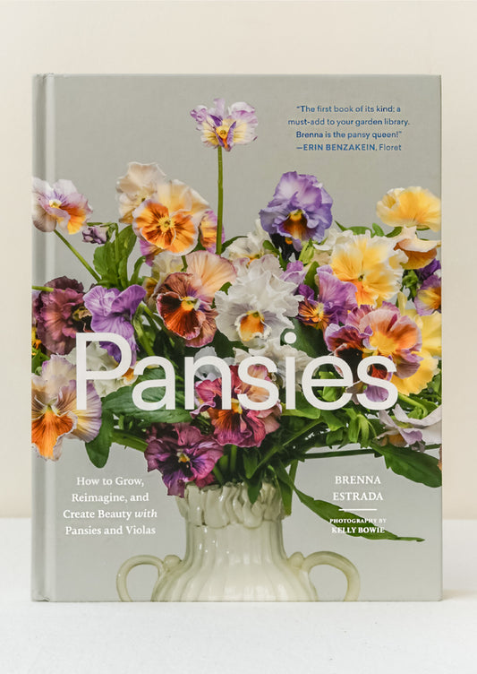 A book titled "Pansies" by Brenna Estrada standing upright on a table.