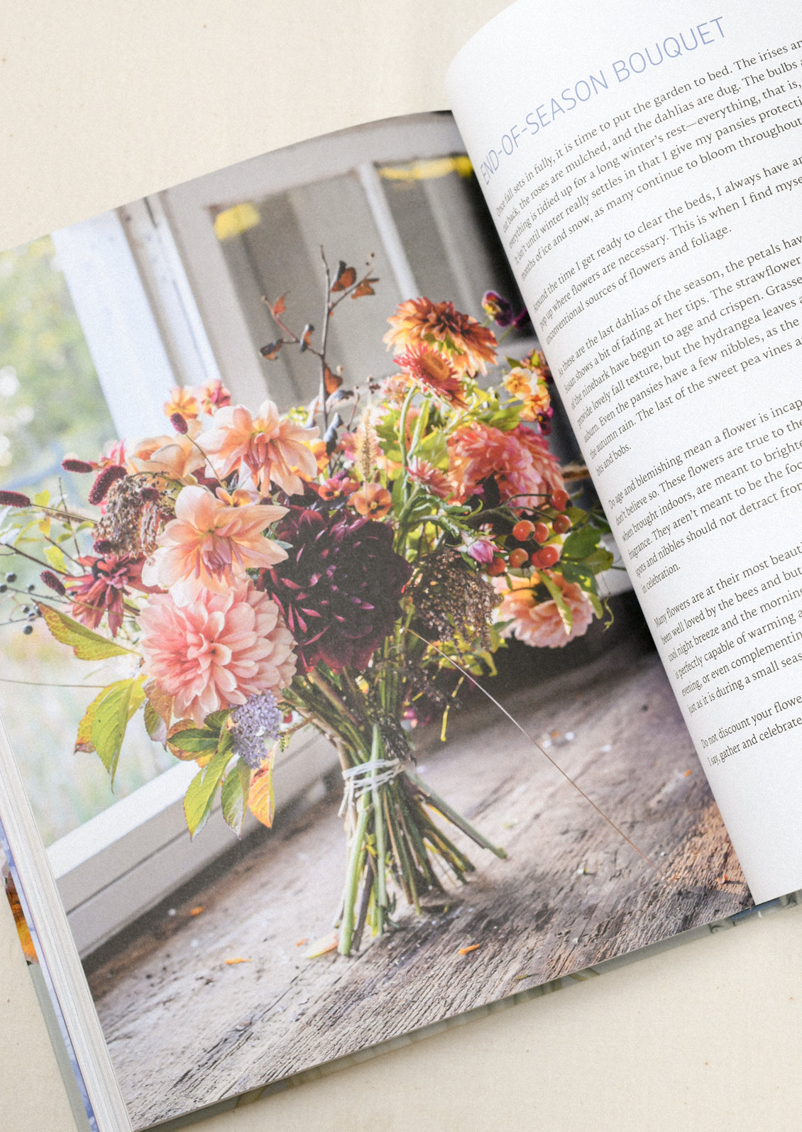 A book open on a table with an image of a bouquet of pansies mixed with other flowers. 