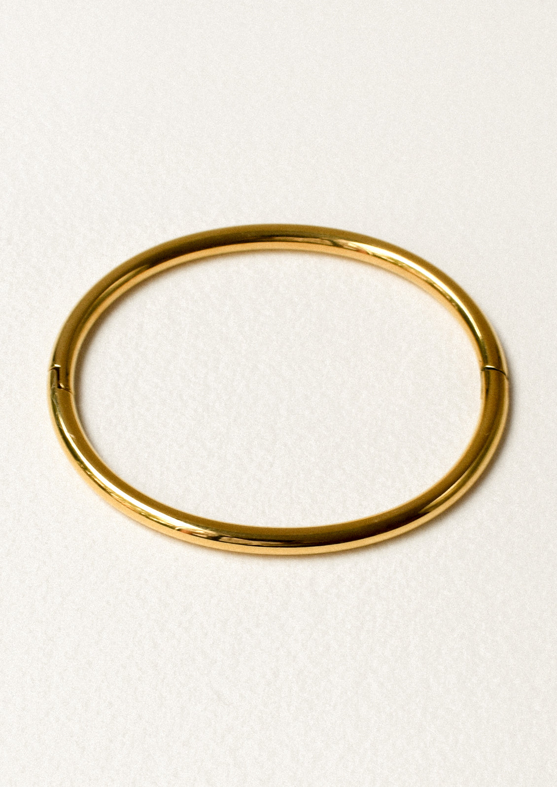 A minimal gold bangle on a white background.