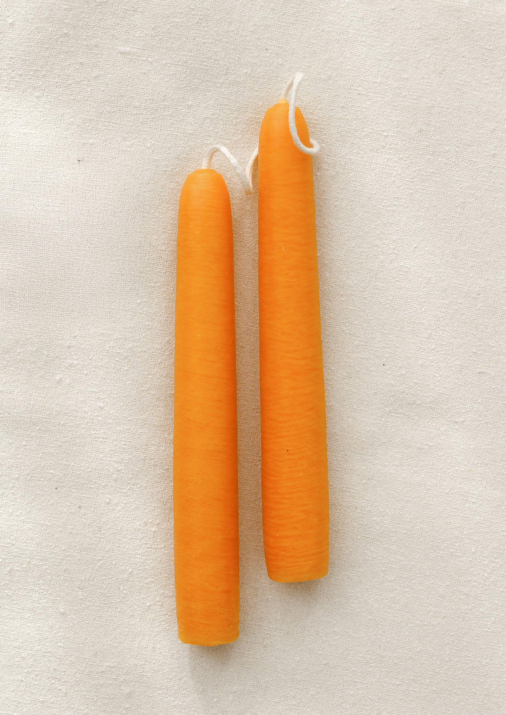 A pair of short orange taper candles.