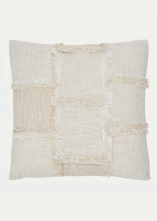 A throw pillow in natural cotton with patchwork detailing in different textures.