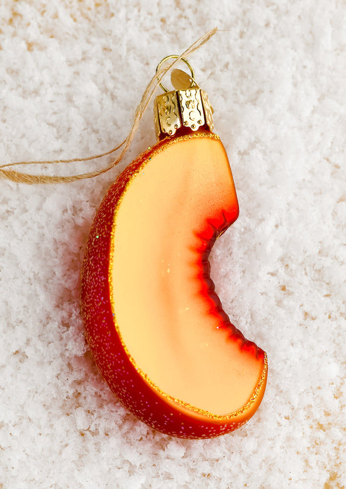 A glass ornament in the shape of a sliced peach.