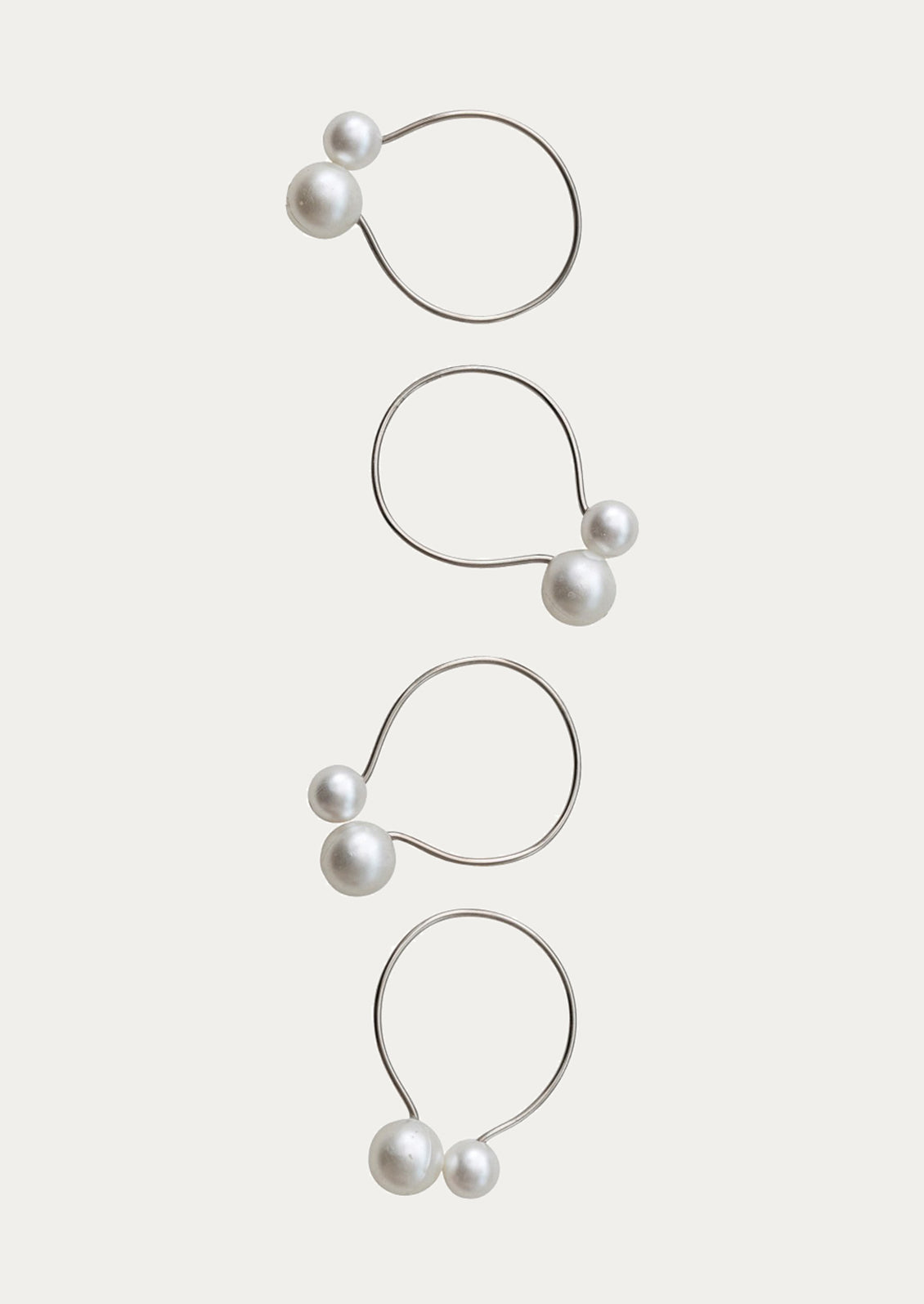 Set of four pearl earrings on a light beige background