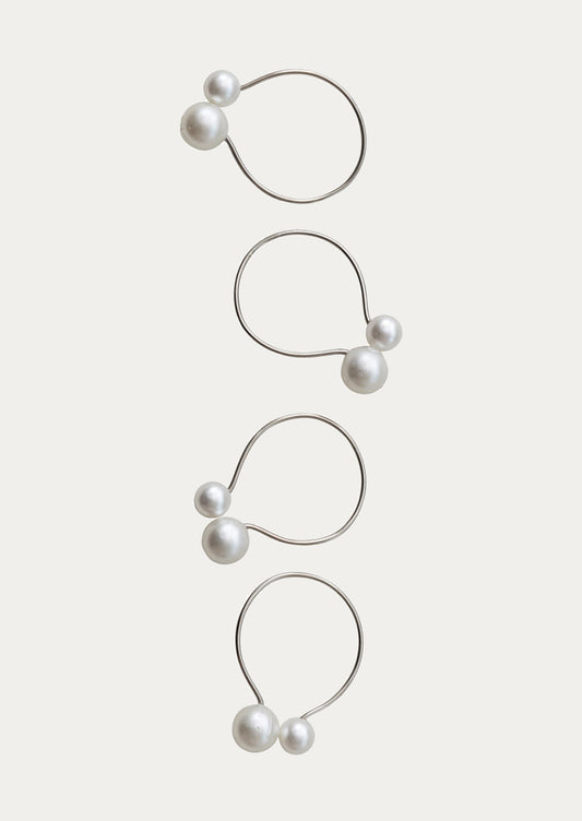 Set of four pearl earrings on a light beige background