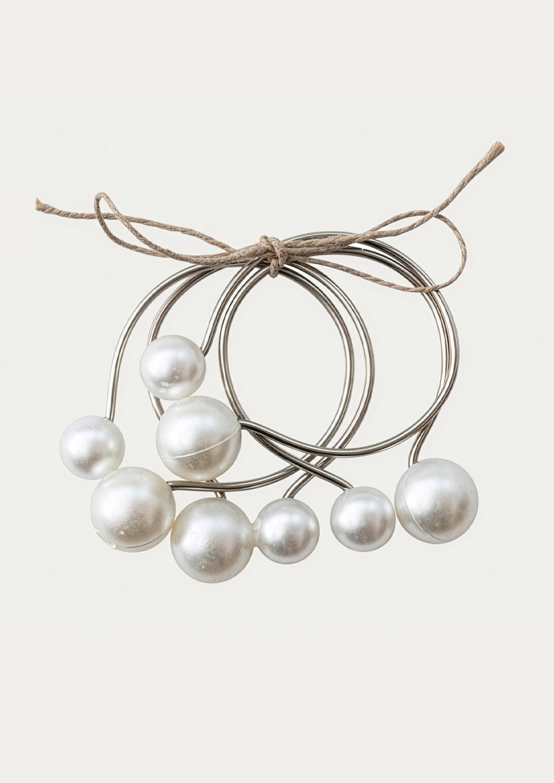 Set of pearl-like beads on metal rings tied with twine on a white background
