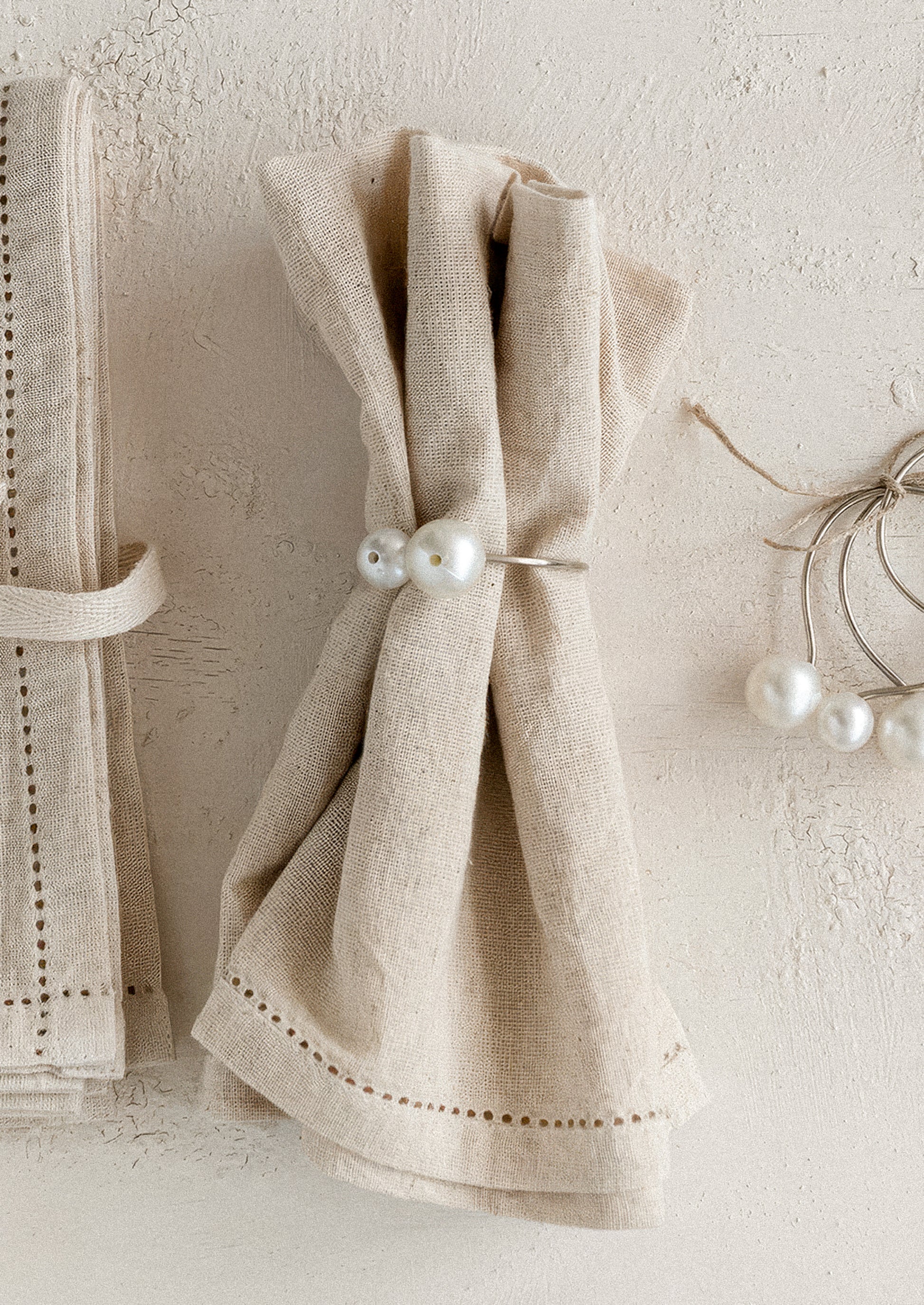 Beige napkin with pearl decorations on a textured white surface
