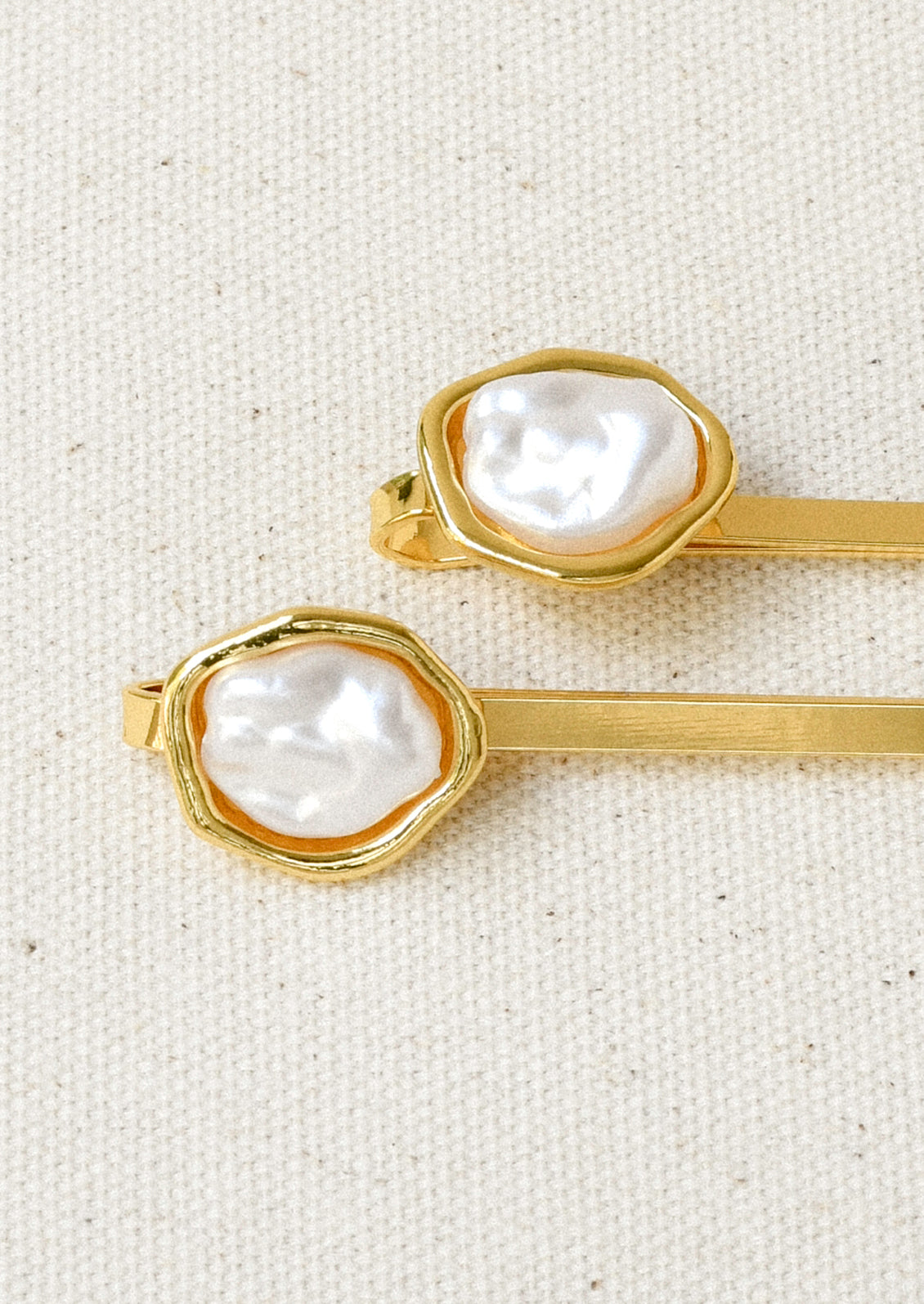 A set of 2 gold hair pins with a faux freshwater pearl on the end of each.