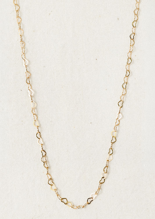A gold necklace composed of tiny hearts linked together in a chain.