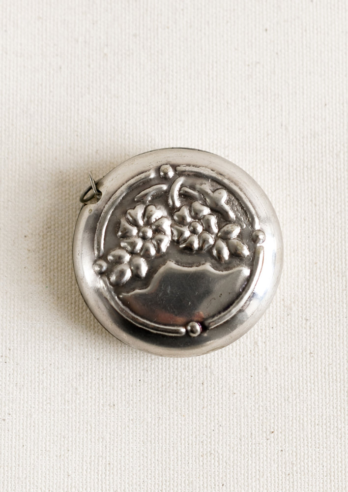 Pewter Flowers: A round silver-tone measuring tape with embossed floral pattern.