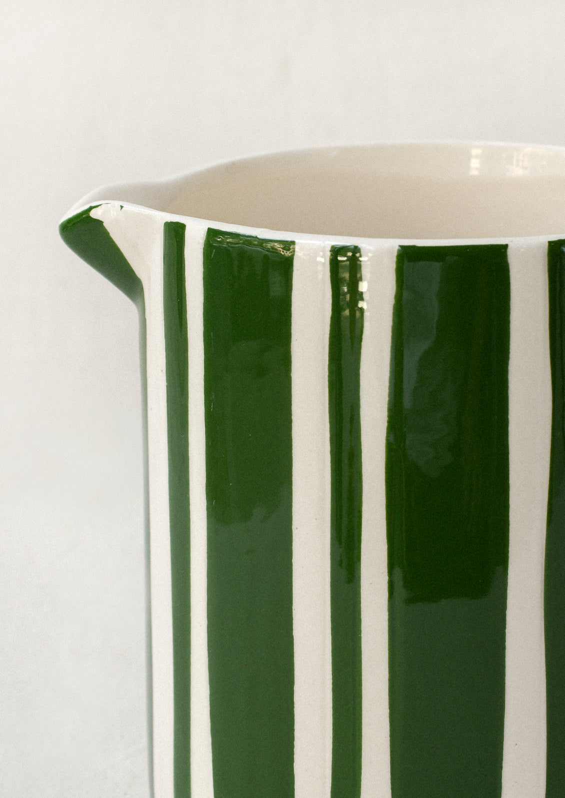 A ceramic pitcher with dark green stripes.