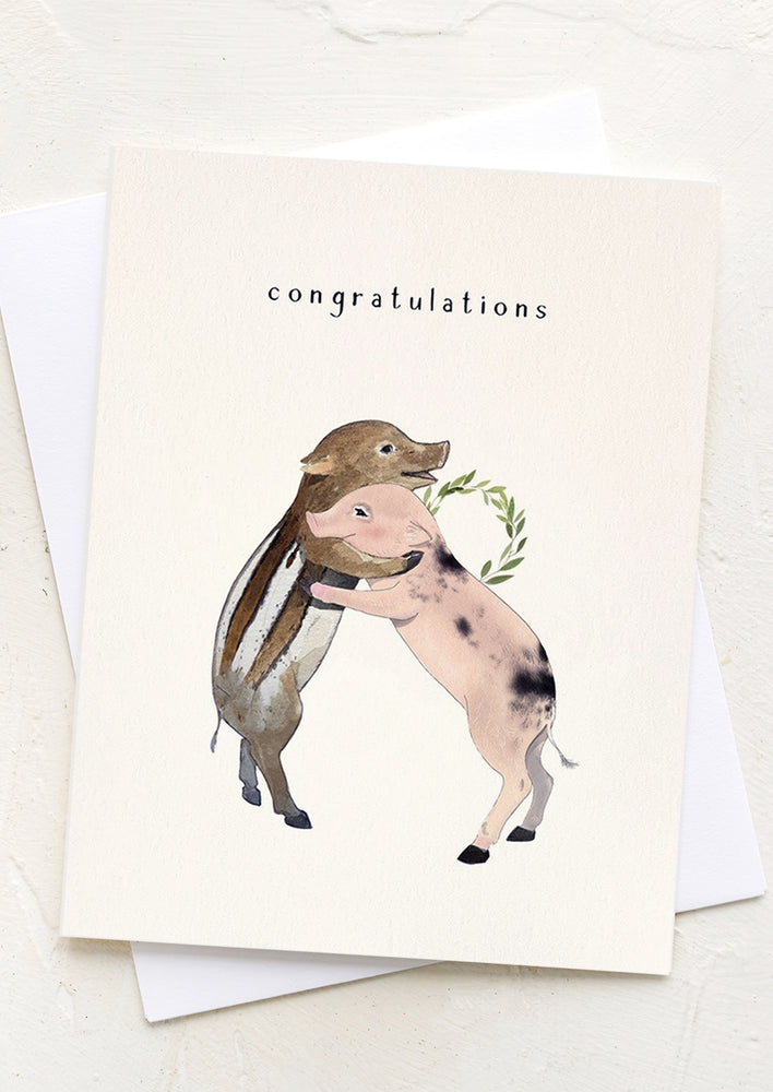 1: An illustrated greeting card with two pigs hugging reading "Congratulations".