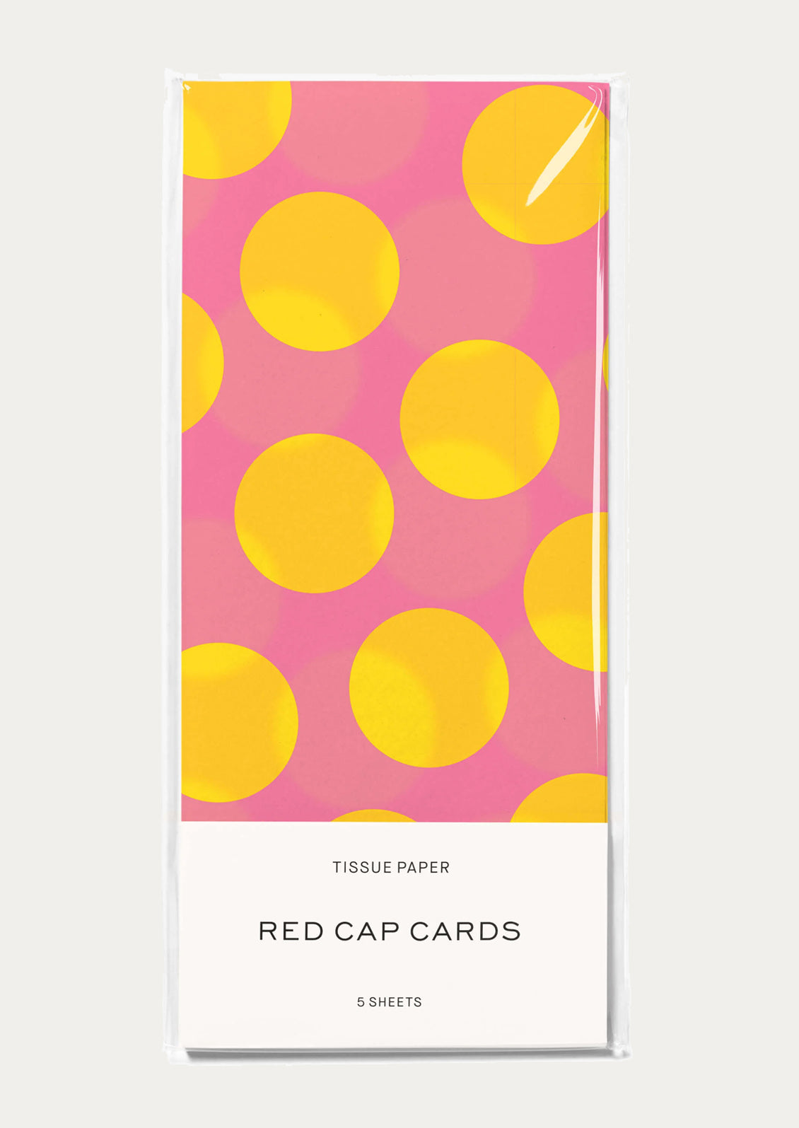 A package of tissue paper featuring a pink background with large yellow polka dots.