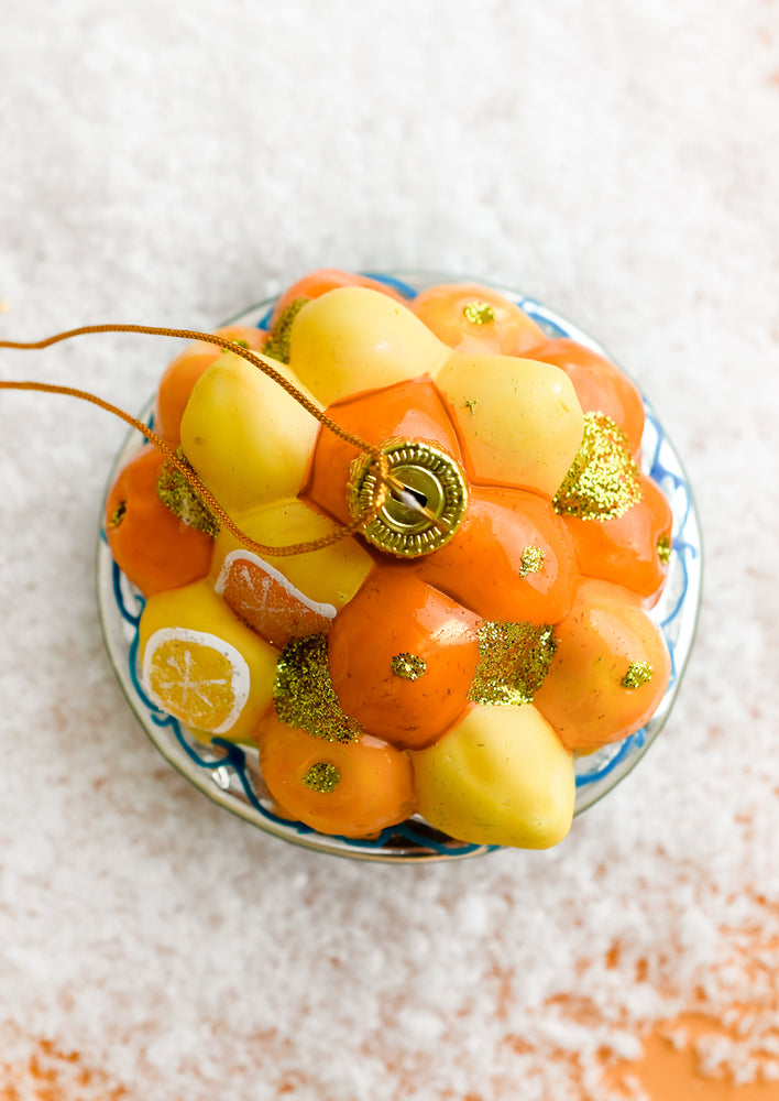 A glass ornament depicting a bowl of lemons and oranges.