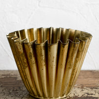 1: A pleated metal planter in distressed brass finish.