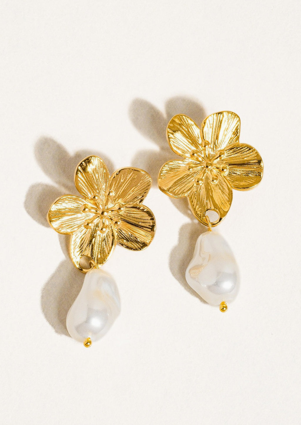 1: A pair of earrings with flower shaped post and dangling pearl bead.
