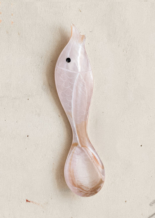 Decorative fish-shaped spoon in pink on a light gray background