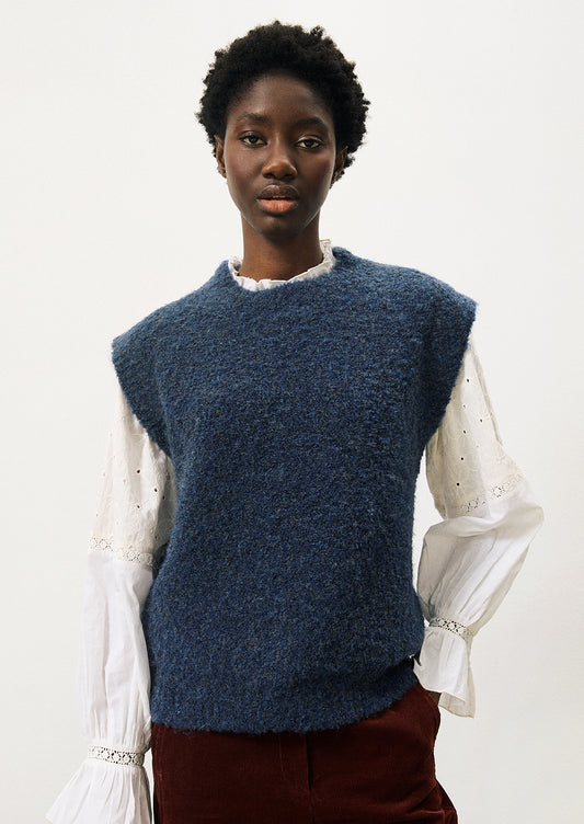 A woman wearing a cap sleeve sweater vest in marled blue knit with boucle texture.