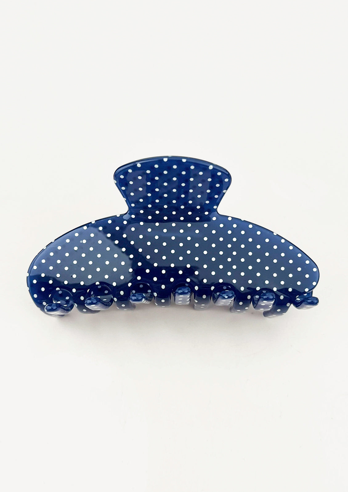 A navy blue hair claw with a white polka dot pattern.
