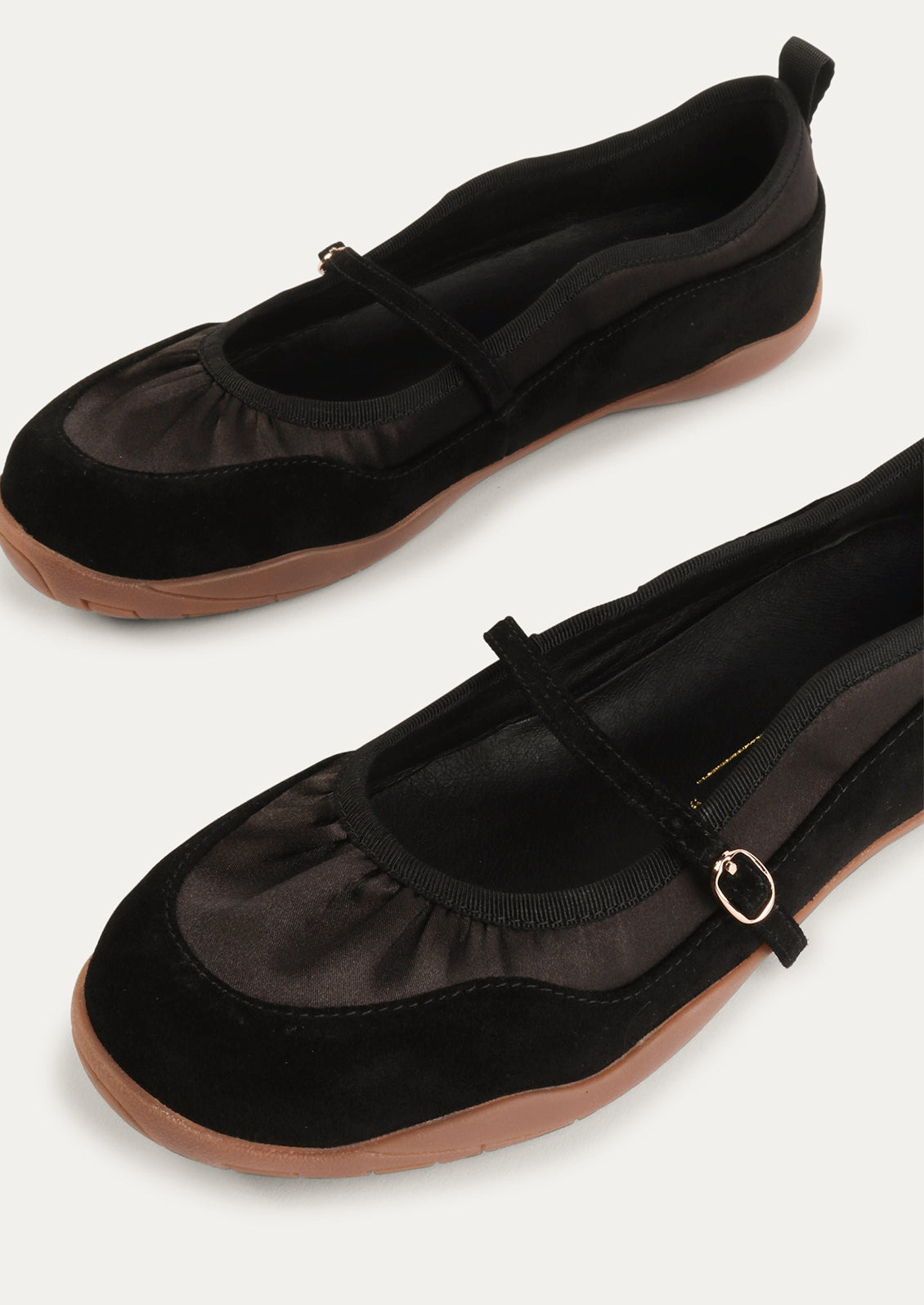 A pair of black shoes that are part sneaker, part ballet flat mary jane. Suede/textile upper with a rubber gum sole.