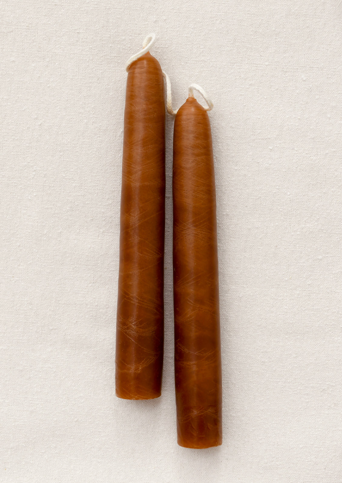 A pair of short light brown taper candles.