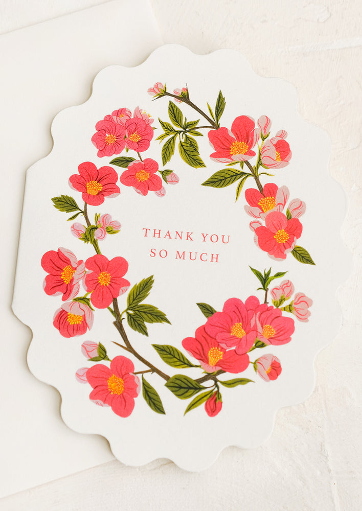 A scalloped oval shaped greeting card with pink floral print, text reads "Thank you so much".