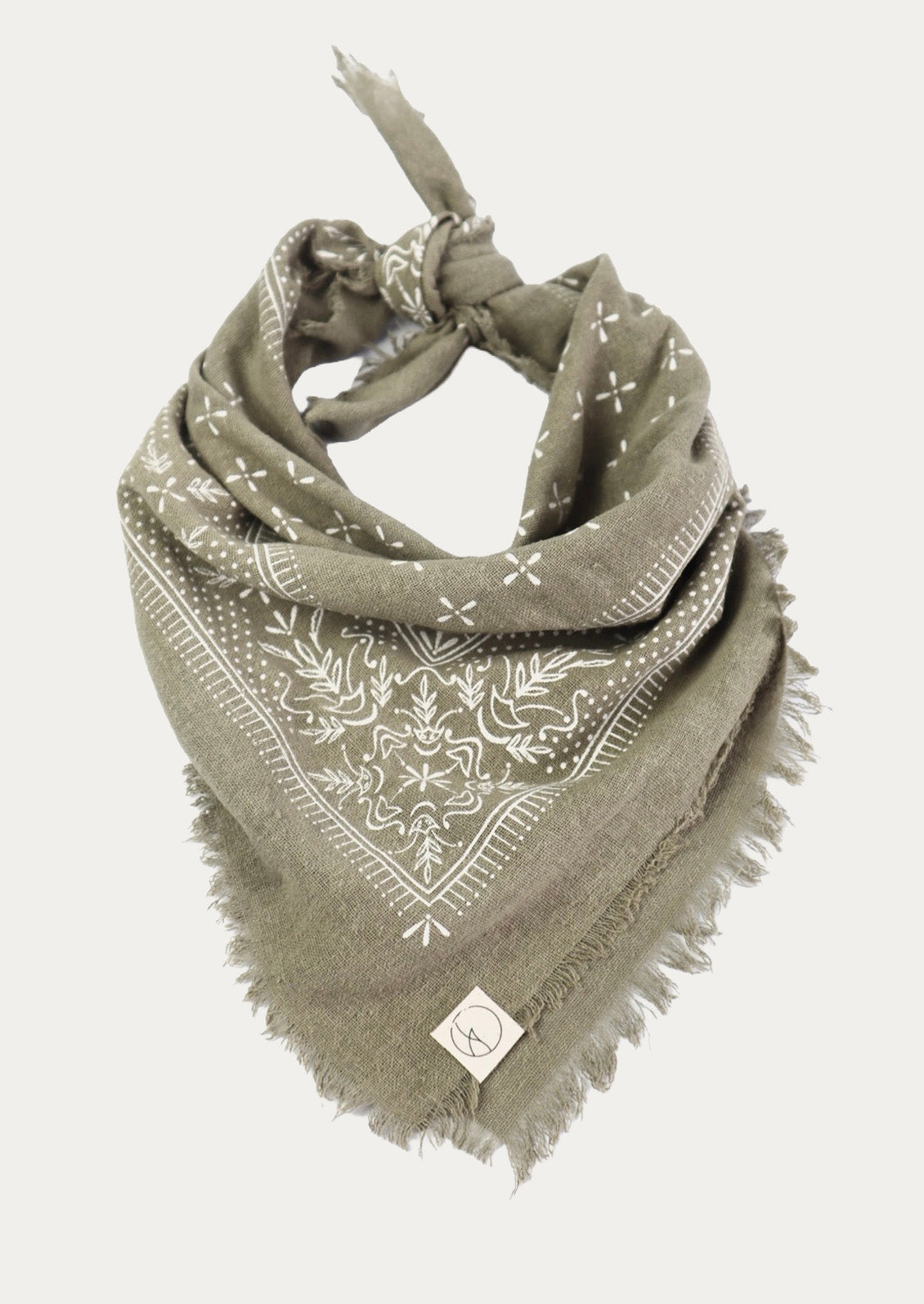 A sage colored patterned scarf tied up as a triangle bandana on a white background.
