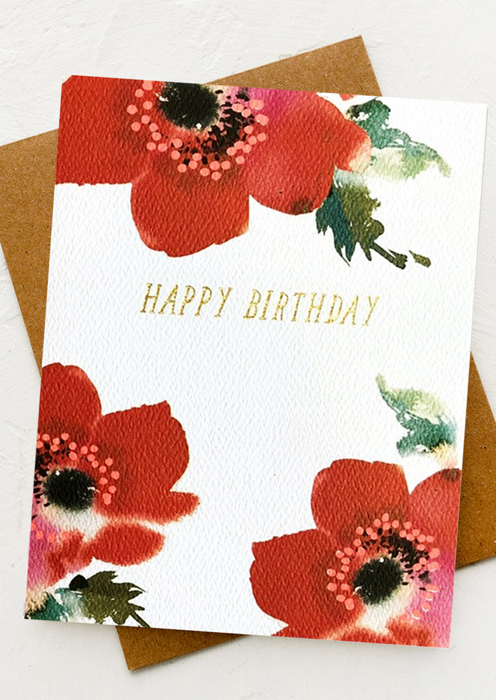 A red anemone printed card with gold text reading "Happy birthday".
