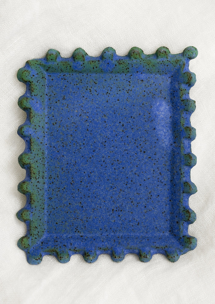 A rectangular ceramic dish in matte blue with decorative trim.