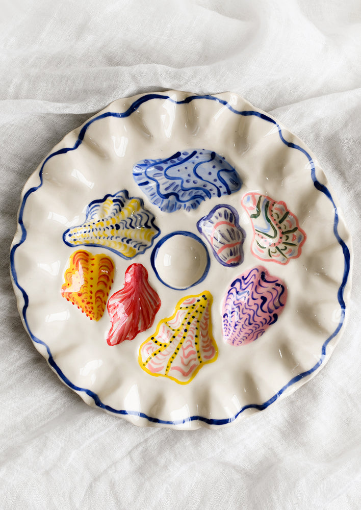 1: A handmade ceramic oyster plate with colorful painted oyster design.