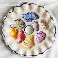 1: A handmade ceramic oyster plate with colorful painted oyster design.