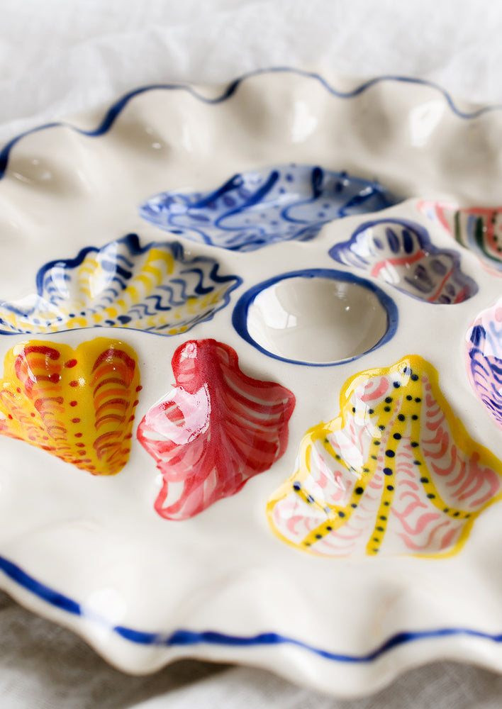 A handmade ceramic oyster plate with colorful painted oyster design.