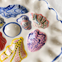 3: A handmade ceramic oyster plate with colorful painted oyster design.