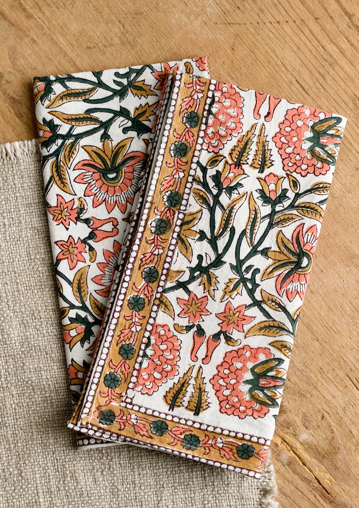 A set of two block printed napkins in pink, emerald and brown print.