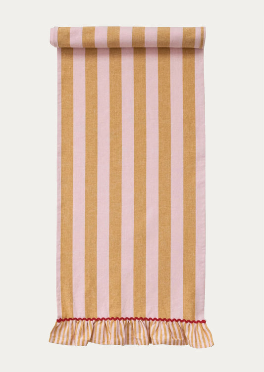 A table runner with wide orange and pink stripe and ruffle trim with red ricrac detailing.