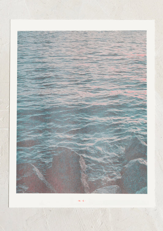 Art print of a seascape with wavy water and rocks.