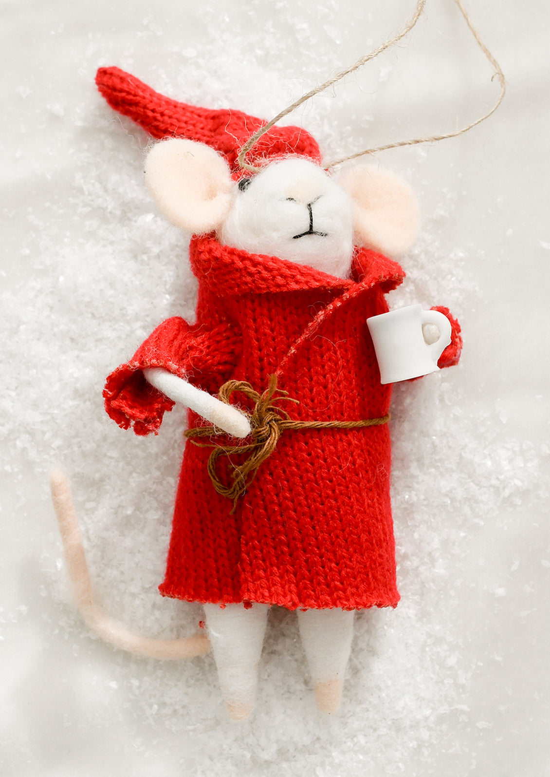 Decorative mouse figurine in a red coat holding a white mug on a light background