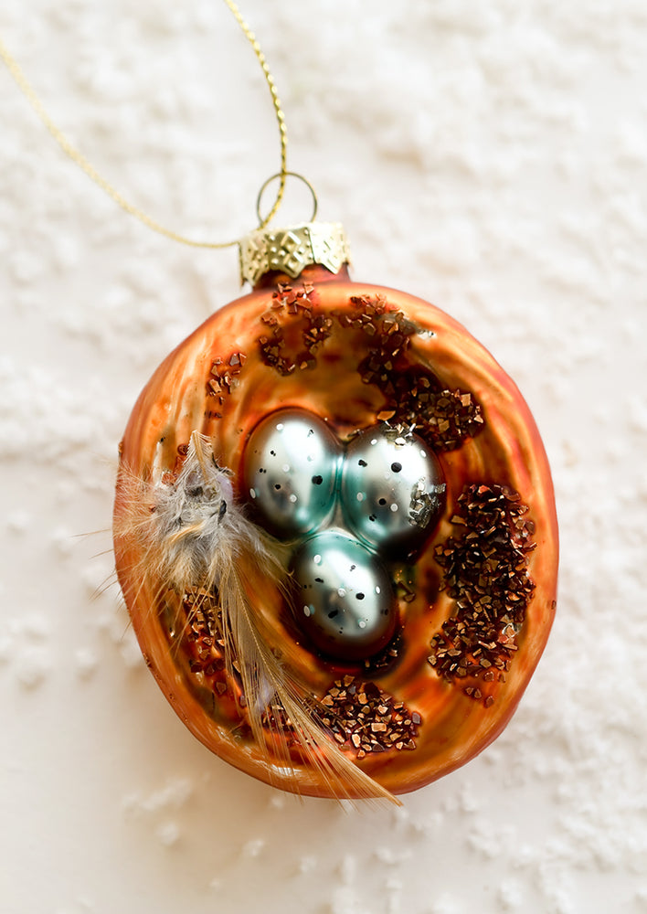 A glass holiday ornament of robin's eggs in a nest.