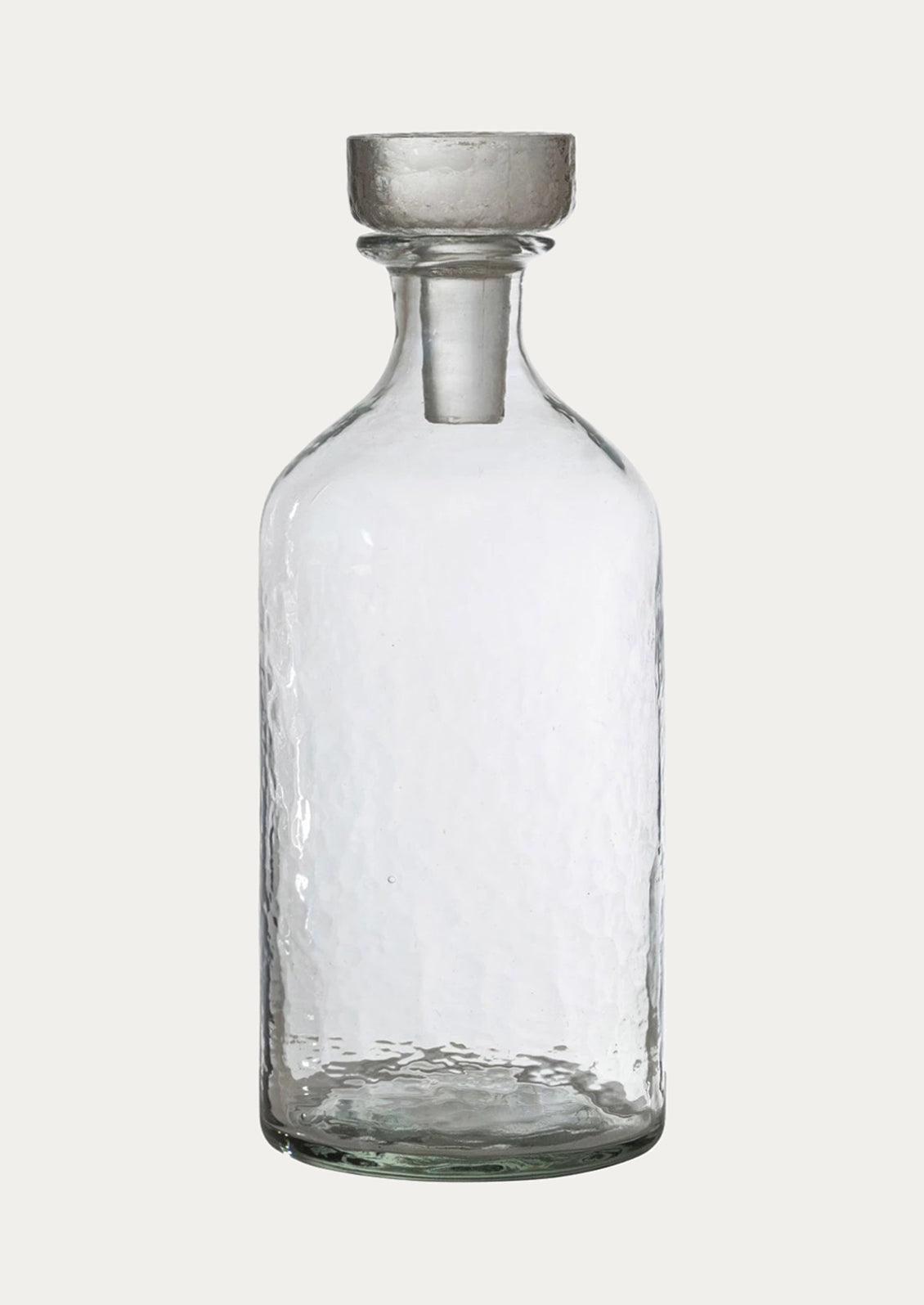 A round bottle in clear glass with pebbled texture and glass stopper.