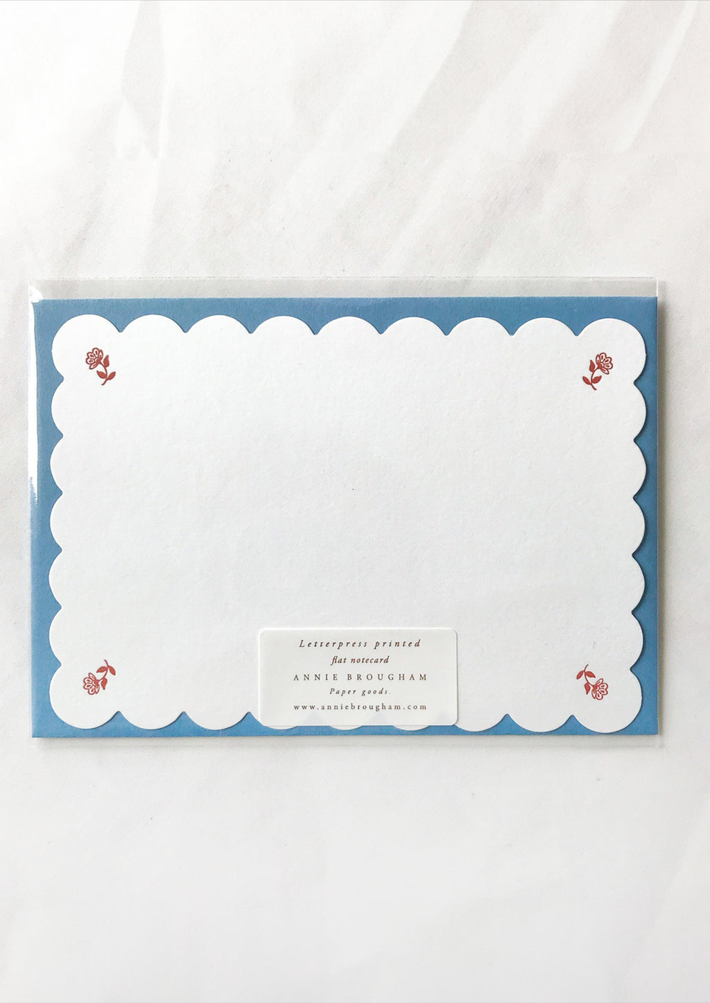 Ruby Floral: A scalloped white notecard with red floral at corners and blue envelope.