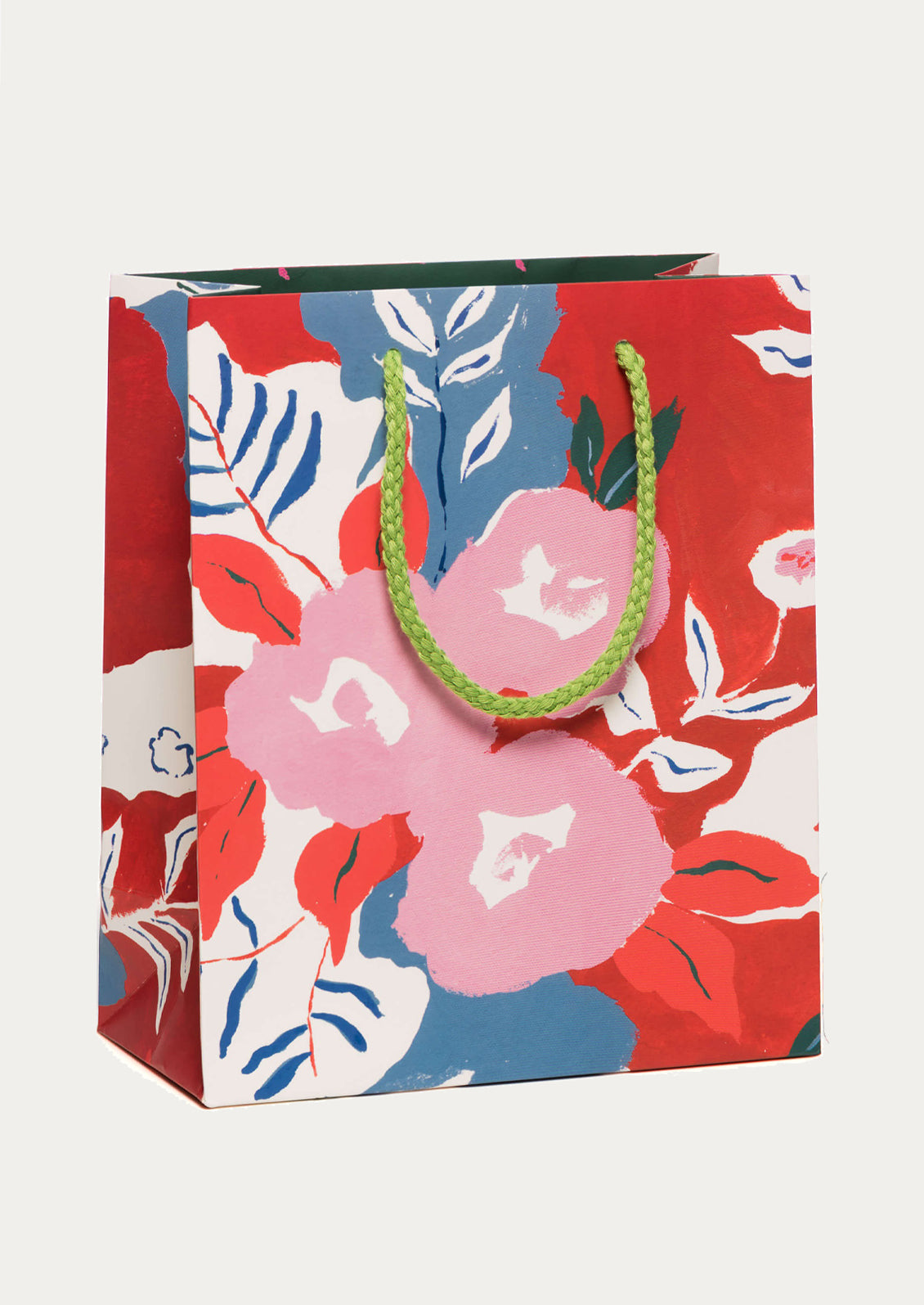 A floral print gift bag in red, pink and blue with green handle.