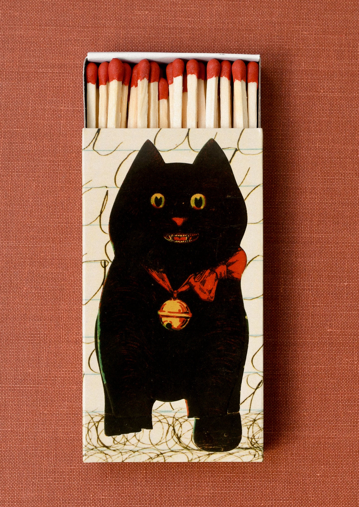 Matchbox with a black cat design holding red tipped long matches.