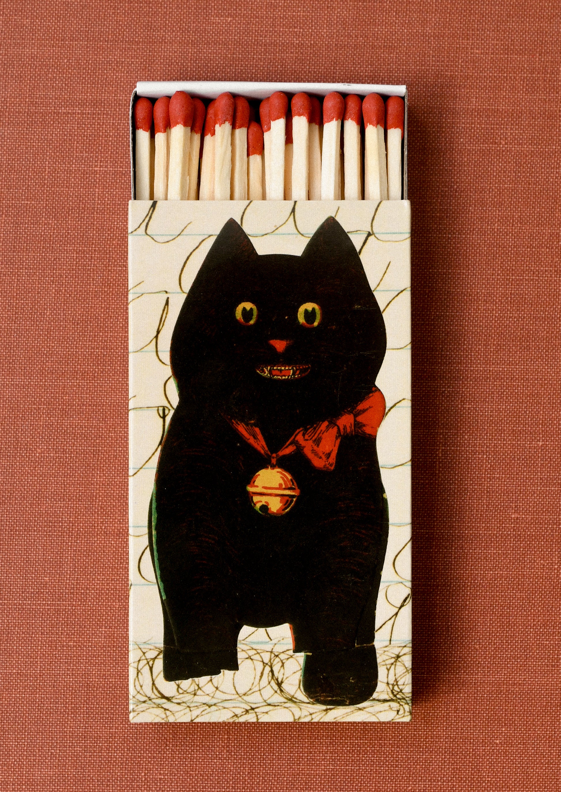 Matchbox with a black cat design holding red tipped long matches.